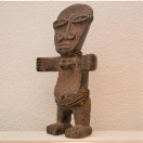 2001010 20ste eeuwse interpretatie van een "Akuaba" beeld - Kameroen <b>Mooie hedendaagse interpretatie van een<i>“Akuaba”</i> vruchtbaarheidsbeeld - Kameroen.</b><br><br>
<b>Afmetingen:</b> H 56 B 26 D 8. <br><br>Akuaba-figuren met schijfvormige kop zijn één van de meest bekende vormen uit de Afrikaanse kunst.<br><br>Deze beeldjes worden in verschillende contexten gebruikt. In de eerste plaats door priesters tijdens ceremonies.<br>Anderzijds dragen ook vrouwen ze op hun lichaam. Ze hopen zo een kind verwekt te krijgen.<br><br> Het platte, schijfvormige hoofd is een sterk overdreven weergave van hun schoonheidsideaal: een hoog, ovaal voorhoofd, enigszins afgeplat door voorzichtige modellering van de zachte schedelbeenderen van de baby.<br>De afgeplatte vorm heeft ook een praktisch doel. Vrouwen dragen deze figuren gewikkeld in een doek tegen hun rug. Het doet denken aan de manier waarop ze in Afrika baby’s dragen.<br><br>De delicate mond is klein en laag op het gezicht gesitueerd en meestal rechthoekig of vierkant weergegeven.<br><br>Traditioneel hebben de meeste Akuaba abstracte, horizontale armen en een cilindrische torso met eenvoudige indicaties van de borsten en navel. De romp eindigt in een basis, in tegenstelling tot menselijke benen.<br><br>De stijl van dit beeld is zeldzaam vanwege de afwijkende vorm. Het is een geslaagde, vrije combinatie door een meester-houtsnijder van de “Akuaba” (Ashanti - Ghana) en “Pygmy” (Tikar - Kameroen) beeldstijlen. De overgrote meerderheid van houtsnijders beperken zich tot het kopiëren van gekende modellen. Het  is uitzonderlijk een nieuw werk te vinden.<br><br>De bovenzijde is voornamelijk Akuaba geïnspireerd, met horizontale armen die naar voor buigen. Het hoofd is niet meer volledig rond en overmaats, maar de ellipsvormige ogen en platte neus volgen nog de traditionele Akuaba stijl. Ook de afgeplatte achterzijde is uitgevoerd volgens traditionele zin. <br>De gebogen benen en uitgewerkte voeten liggen dan meer in lijn met de “Pygmy” stijl.<br><br>Figuren zoals deze worden gezien als een recente twintigste-eeuwse innovatie binnen de sculpturale traditie van de Akuaba. 
 2001010-01.jpg