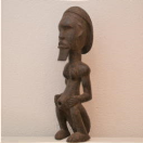 2001014 "Ntumu" reliekbewaarder van de Fang uit Gabon <b>Mooi uit tropisch hardhout gesneden reliekbewaarder.<br><br>Afmetingen in cm:</b> H 57 B 15 D 15 <br><br> Deze mannelijke reliekschrijnfiguur is zeer kenmerkend voor de Ntumu-stijl.<br>Ondanks zijn schijnbare eenvoud, vertoont het zeer bekwame technieken. Het beeld heeft een extreem langwerpige cilindrische torso (het meest typische kenmerk van de Ntumu-stijl) en het bevat de 'longiforme' (de schouders strekken zich uit en creëren een rechtlijnige configuratie), typisch voor de Ntumu-stijl.<br> De gladde armen zijn relatief broos. Dijen en kuiten werden ingekort zodat het achterwerk van het hurkend beeld de grond raakt en samen met de voeten een basis vormt om de figuur in staat te stellen als bewaker op de rand van het reliekschrijn te zitten.<br> De overdreven verhoudingen tussen lichaamsdelen zijn bedoeld om symbolische nadruk te leggen op belangrijke delen van het lichaam, bijvoorbeeld het grote hoofd als de zetel van wijsheid en vitaliteit en de uitstekende navel als een herinnering aan het verband met de dode voorouders van generatie op generatie. 2001014-01.jpg